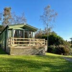 Holiday caravan with a wooden deck on a green lawn