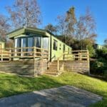 Holiday caravan with a wooden deck set in a grassy
