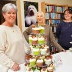 three women showcasing a display of gourmet cupcakes
