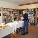 A cosy indoor gathering at a luxury holiday home, featuring a book-filled library