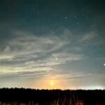 Starry night sky over a holiday park with the moon casting a soft glow on the horizon