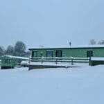 a snow-covered cabin with a wooden deck