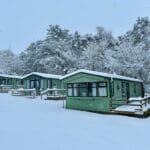 A row of cozy green cabins covered in a thick layer of snow