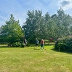 Three people playing croquet in a garden