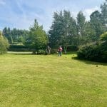 Three people playing croquet in a sunny garden