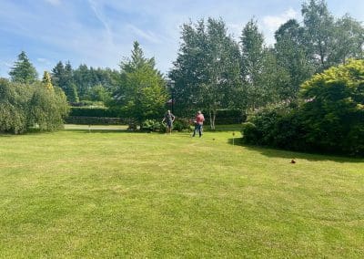 Three people playing croquet in a sunny garden