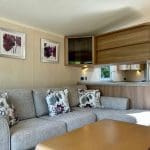 Comfortable lounge area with soft seating and modern kitchen in a caravan at Warren Forest Park