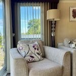 Comfortable armchair with a floral cushion inside a caravan at Warren Forest Park