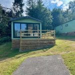 Exterior view of a modern caravan with a wooden deck at Warren Forest Park
